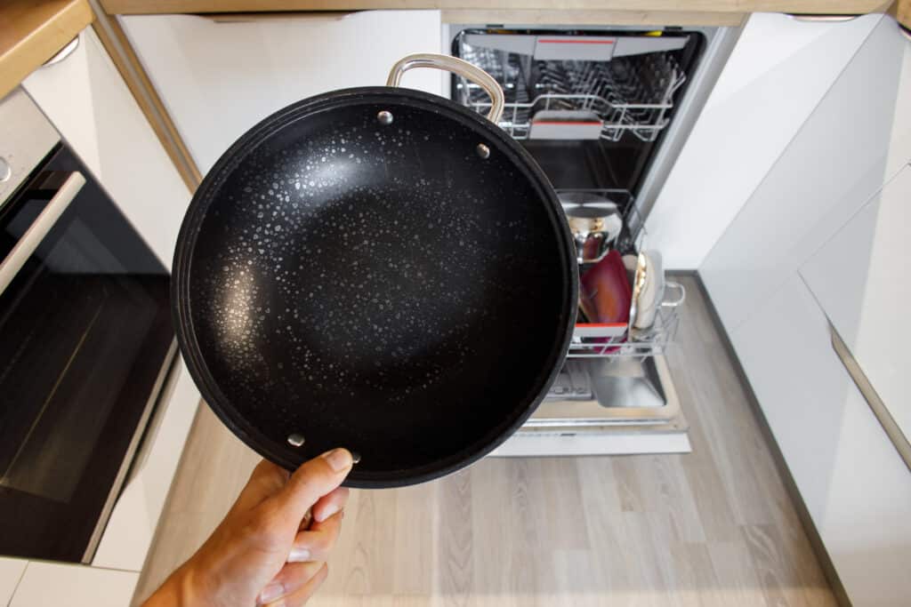 frying pan with white flakes from hard water while washing in the dishwasher in a modern smart kitchen